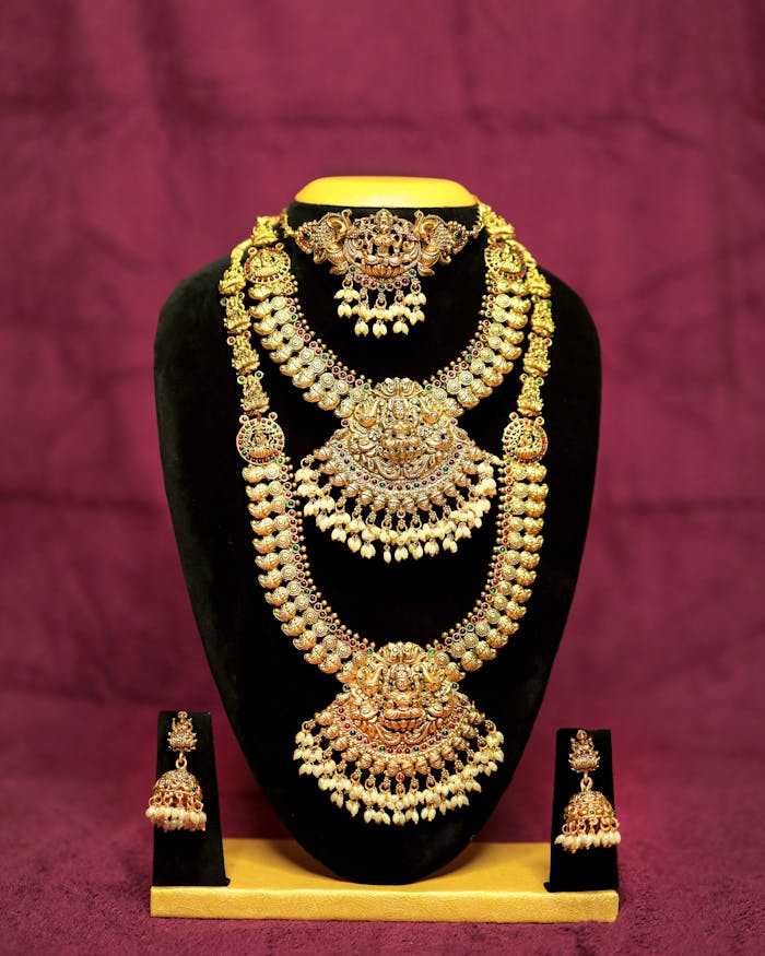 Lavish gold bridal jewelry set with intricate designs on a velvet stand.