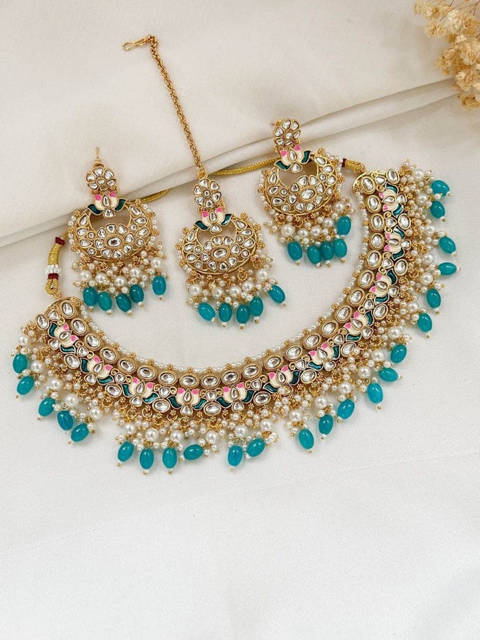 heros-img Elegant traditional Kundan necklace and earrings set with blue gemstones, perfect for cultural events.